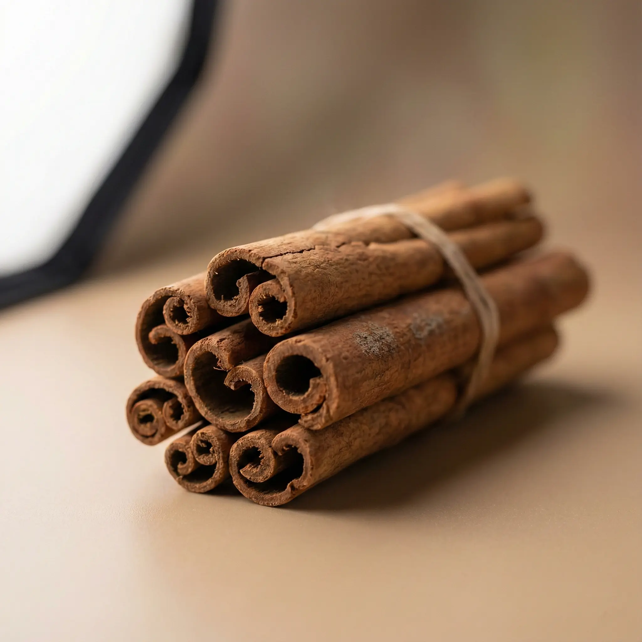 Close-up of a hand-tied bundle of Premium Ceylon Cinnamon Quills (Alba/C5 Grade), highlighting the intricate tight scrolls and thin bark layers typical of high-quality Sri Lankan export spice.
