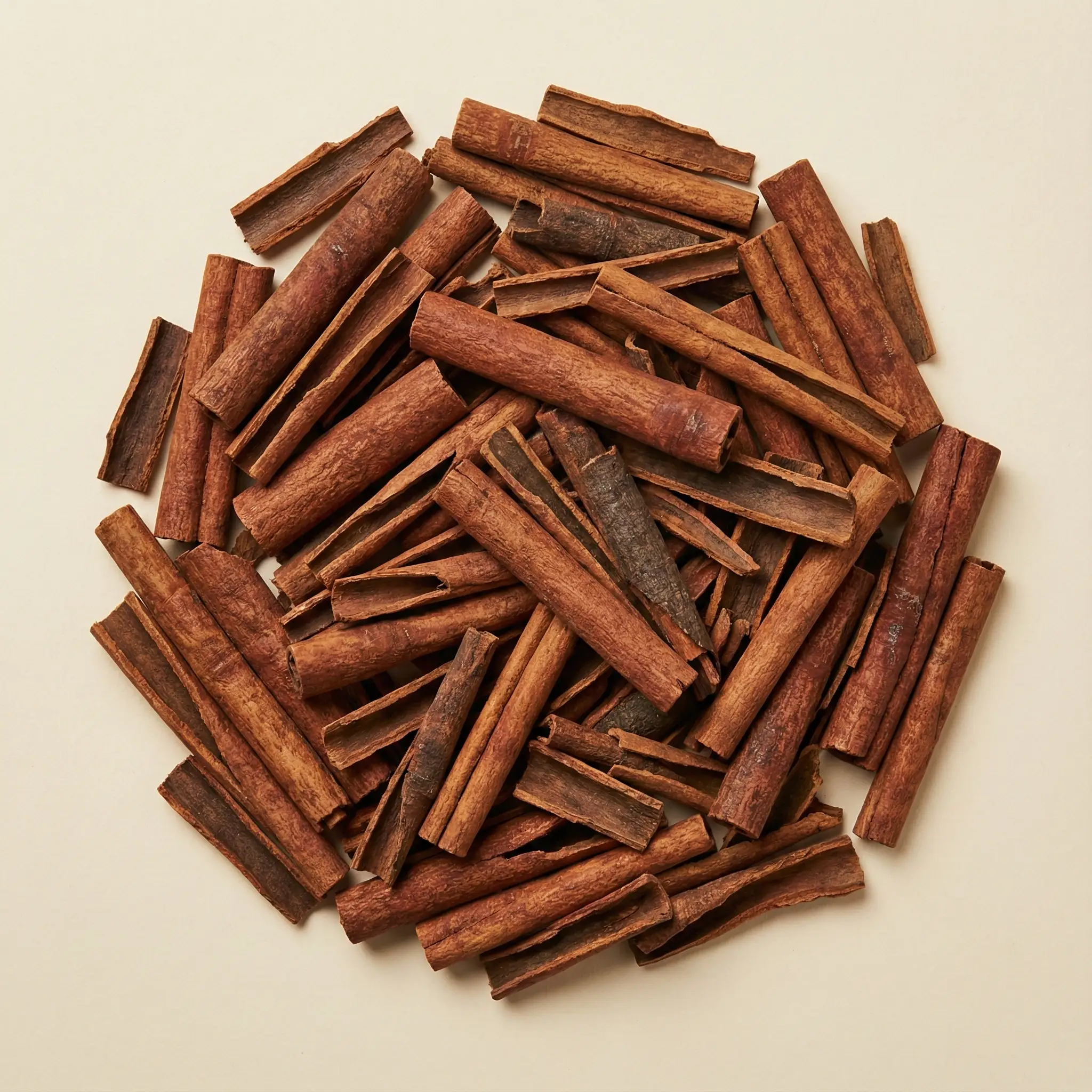 Top-down view of sorted Premium Ceylon Cinnamon Quillings (Grade 1 broken segments) arranged in a uniform pile, displaying clean bark texture and consistent tan color ideal for commercial spice grinding, tea blending, and oleoresin extraction.